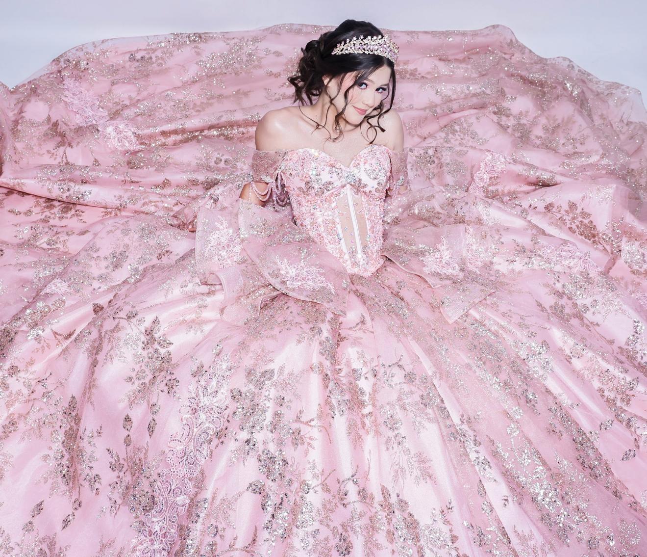 Aneth seated amid the flowing train of her sparkling pink gown